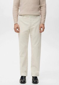 Pantalones de pana beige con dise�ño de pierna recta, acompañados de un cinturón y bolsillos delanteros, combinados con mocasines negros.