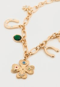 Κολιέ αλυσίδας σε χρυσό τόνο με μενταγιόν λουλούδι που διαθέτει πολύχρωμους πολύτιμους λίθους, έναν στρογγυλό πράσινο λίθο και διακοσμητικές λεπτομέρειες σε σχήμα πετάλου.