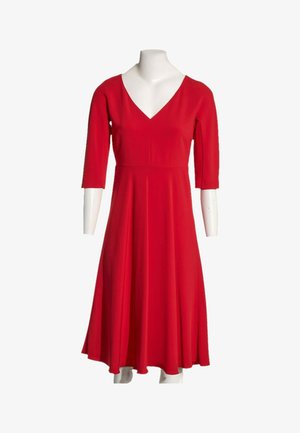 Robe rouge mi-longue aux genoux avec manches trois-quarts et décolleté en V, présentée sur un mannequin blanc sur fond uni.
