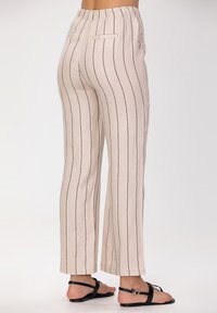 Pantalons en lin couleur crème avec des rayures verticales bleu marine, à coupe décontractée, taille élastique et deux poches à l'arrière.