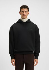 Felpa nera con cappuccio realizzata in tessuto morbido e dalla vestibilità comoda, dotata di cordini per il cappuccio e un logo discreto all'altezza del petto. Rifinita con polsini a coste.