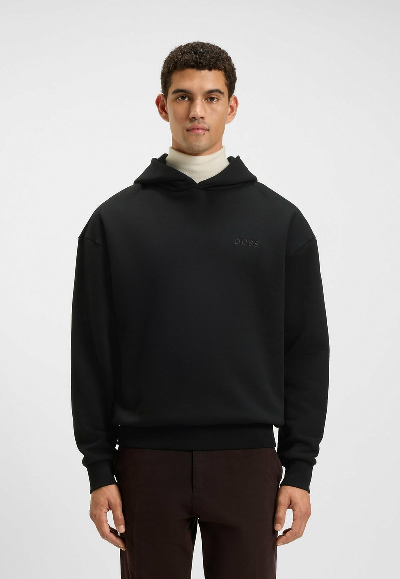 Felpa nera con cappuccio realizzata in tessuto morbido e dalla vestibilità comoda, dotata di cordini per il cappuccio e un logo discreto all'altezza del petto. Rifinita con polsini a coste.