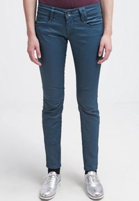 Slim-fit teal jeans van zachte stof, met een knoopsluiting, voorzakken en gestikte details langs de naden.