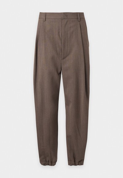Pantalon marron sur mesure avec plis, passants pour ceinture et poignets élastiqués, présenté sur fond blanc.