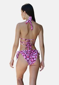 Roze luipaardprint bikini met een halternek en rugbandjes. De top heeft dunne bandjes en de onderkant heeft verstelbare zijbandjes.