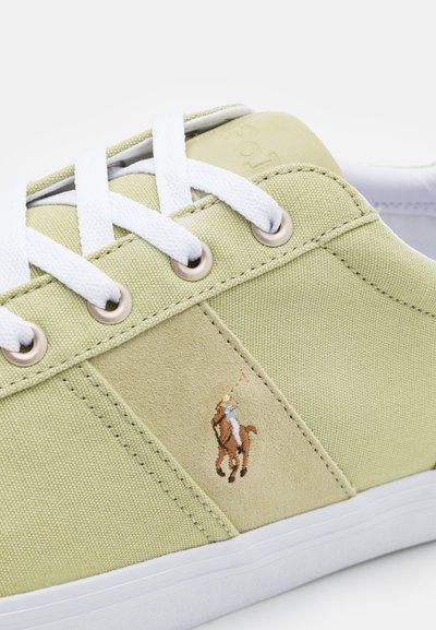 Sapatilhas de lona verde limão com atacadores brancos, detalhe em camurça bege e logótipo de cavalo bordado. Apresentam ilhós de metal e tecido texturizado.