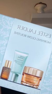 Estee Lauder Morning Glow Routine -sarja, joka sisältää kolme tuotetta: tumma seerumi, vaaleanvihreä geeli ja meripihkainen voide, kaikki kullanvärisin yksityiskohdin.