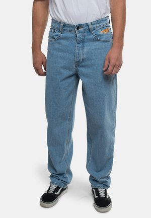 Lyseblå, løstsiddende jeans med lige ben-design, der har en knaplukning og frontlommer. Kombineret med sorte og hvide sneakers.