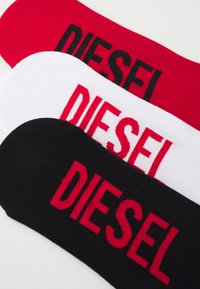 Kolm paari sokke punases, valges ja mustas värvitoonis. Iga paari peal on silmatorkavalt esitatud sõna "DIESEL" kontrastsetes värvides.