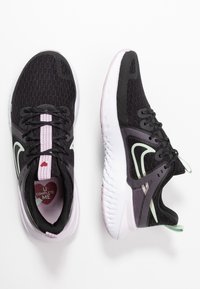 Des chaussures de sport noires avec un empeigne en maille, des accents roses et verts, et une semelle blanche. Présente un design en forme de cœur sur la semelle intérieure et des lacets contrastants.