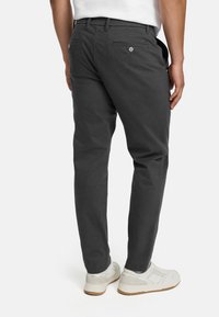 Šedé bavlnené nohavice s priamym strihom, vybavené dvoma zadnými vreckami a jemnými švami. Nosené s bielymi teniskami.