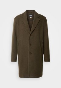 Olivgrön ylledräkt med kavajslag, enfärgad design, tre framsidknappar och sidofickor. Slät textur med minimal utsmyckning.