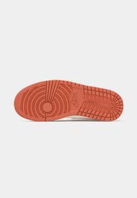 Sole tenisky Nike, která má texturovanou gumovou podrážku v živé oranžové barvě s kruhovými a liniovými vzory pro lepší trakci.