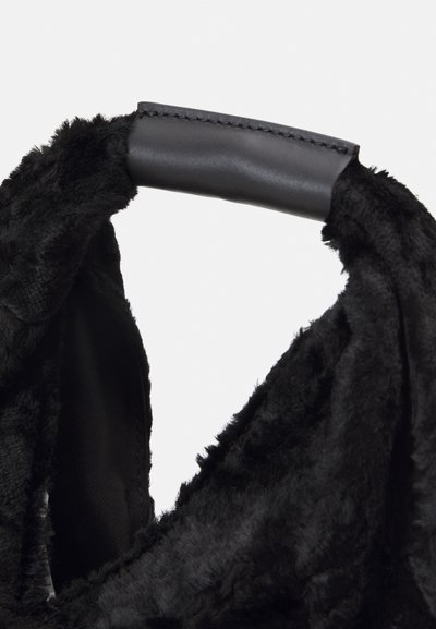 Mala de pelúcia preta com uma pega de couro preto liso, apresentando uma textura suave e uma forma elegante e estruturada. Sem hardware visível.