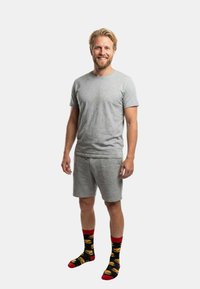 Graues Baumwoll-T-Shirt- und Shorts-Set, kombiniert mit schwarzen Socken mit Burger-Mustern und roten Akzenten. Einfaches, legeres Design.
