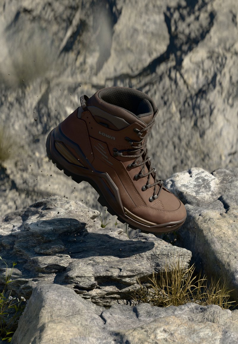 Bota de caminhada castanha com parte superior sintética, design de atacadores, colarinho acolchoado e sola texturizada, colocada sobre terreno rochoso.