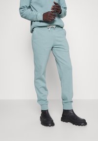 Lichtblauwe sweatpants met elastische boorden en een tailleband met koord, gecombineerd met zwarte chunky laarzen met een gestructureerde zool.