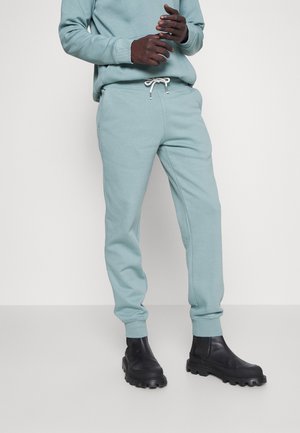 Light blue sweatpants with elastic cuffs and drawstring waist, paired with black chunky boots featuring a textured sole.