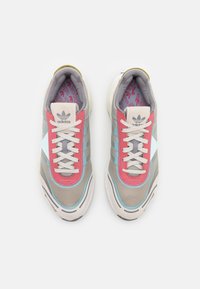 Adidas-sneakers med grått tygöverdel, rosa och turkosa accenter, vita snören och ett mönstrat inre.