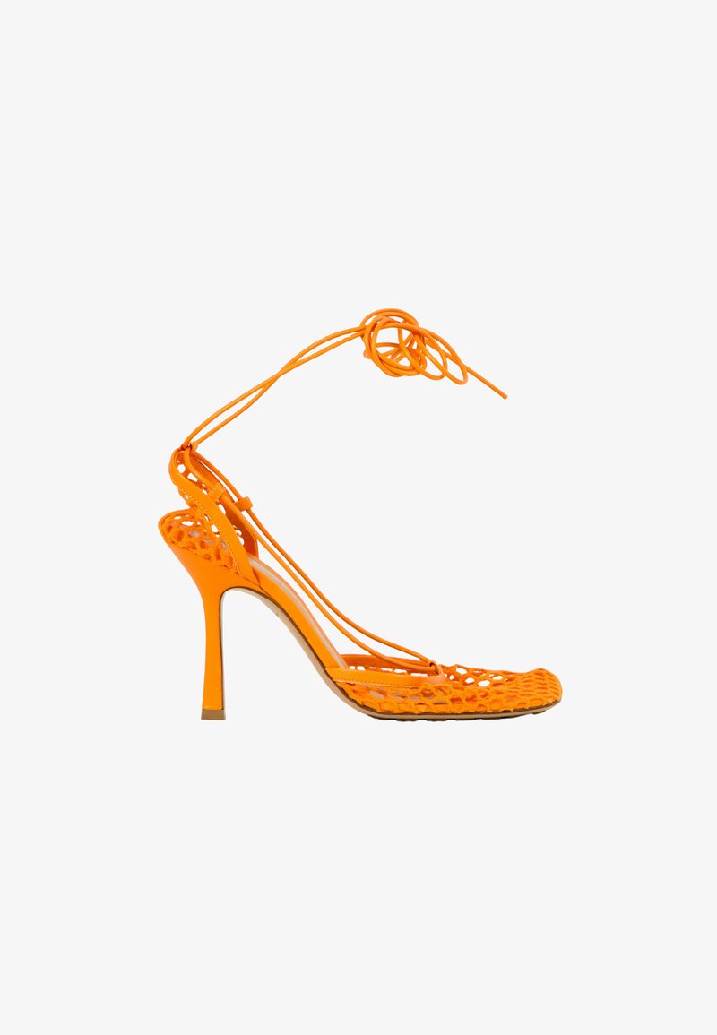 Sandale à talon haut orange avec des brides tressées et un lien à la cheville, orteil ouvert et talon aiguille fin.