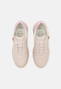 Adidași bej deschis cu un finisaj din piele netedă, având șireturi albe, un accent roz la guler și un fermoar lateral aurie.