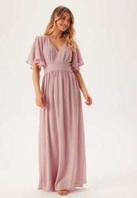 Lichtroze maxi-jurk met korte, vleugelachtige mouwen, diepe V-hals, cinched taille en vloeiende rok, gemaakt van een lichte, gestructureerde stof.