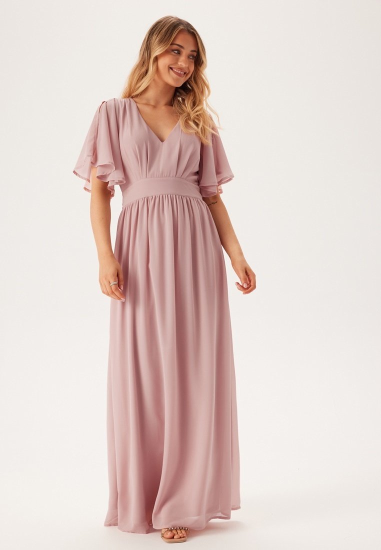 Lichtroze maxi-jurk met korte, vleugelachtige mouwen, diepe V-hals, cinched taille en vloeiende rok, gemaakt van een lichte, gestructureerde stof.