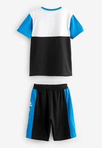 T-shirt noir et blanc avec des manches bleues, associé à un short noir avec des panneaux latéraux bleus et un logo. Tissu en coton, design décontracté.
