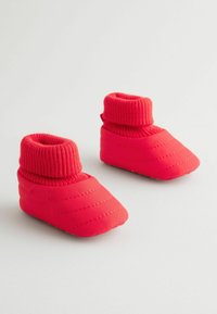 Røde spædbørnssko med quiltet polstring og ribbet strikkrave. Blødt materiale og slip-on design, der har en buet tåform og tekstureret sål.