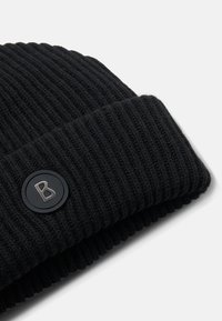 Sort strikket beanie-hat med ribbet tekstur og foldet manchet. Har et rundt sort logo med en sølv 'B'-detalje på siden.