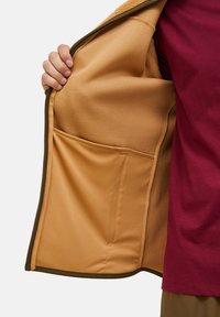 Fleecegefüttertes Innenfutter in Beige mit glatter Textur, ausgestattet mit einer Seitentasche. Der Außenstoff ist olivgrün mit einem plüschigen Kragen.