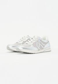Scarpe da atletica argentate con una combinazione di materiali lucidi e in rete, caratterizzate da dettagli grigi, superficie texturizzata e suola in gomma bianca.