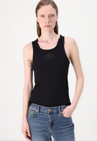 Schwarzes geripptes Tanktop mit klassischem Rundhalsausschnitt und kleinem Logo in der Mitte, kombiniert mit hellblauen Denim-Jeans.