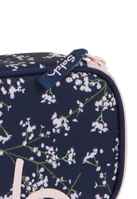 Navy floral print cosmetic bag with white flowers, pink zipper, and a tag labeled "Satch." Rectangular shape with textured fabric.
