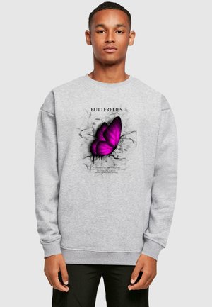 Grey sweatshirt featuring a large purple butterfly graphic with black accents and text above, on a smooth fabric with ribbed cuffs.