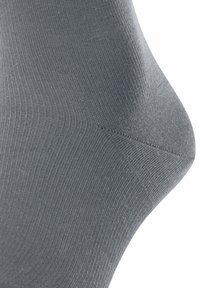 Calzino grigio con una superficie liscia e a coste; presenta una cucitura della punta angolare e un design aderente senza cuciture.