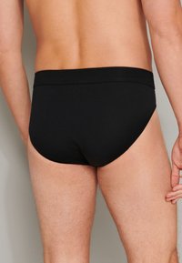 Caleçons noirs en coton avec une taille élastique lisse, offrant une coupe ajustée et un design minimaliste, sans motifs ni accents visibles.