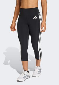 Crne kapri helanke s visokim pojasom imaju bijele pruge u tri trake duž vanjskih strana. Teksturirani, rastezljivi materijal za udobnost.