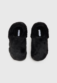 Pantofole nere pelose con texture morbida, design a chiusura posteriore e logo sulla soletta. Forma arrotondata, imbottite per il comfort, adatte per l'uso interno.
