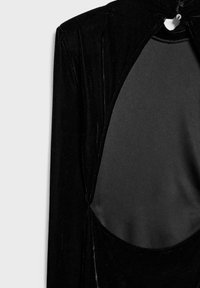 Schwarzes Samtkleid mit ausgeschnittenem Rücken, glatter Textur und Knopfverschluss am Hals, mit einer figurbetonten Silhouette.