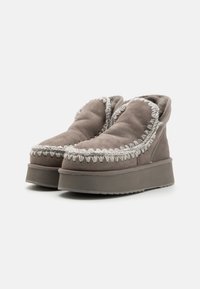 Stivaletti alla caviglia in suede grigio con suola piatta spessa, cuciture decorative e un colletto morbido e arrotondato per un maggiore comfort.