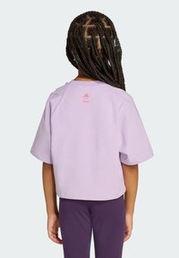 Lilla lühikeste varrukatega crop-top ümmarguse kaelusega. Tagaküljel on roosa Adidas'i logo ja "Disney" tekst. Pehme puuvillane materjal.
