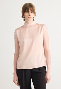 Top senza maniche, con collo alto, realizzato in morbido satin di un delicato rosa chiaro. Presenta un fit rilassato con una texture liscia e dettagli di cucitura minimi.