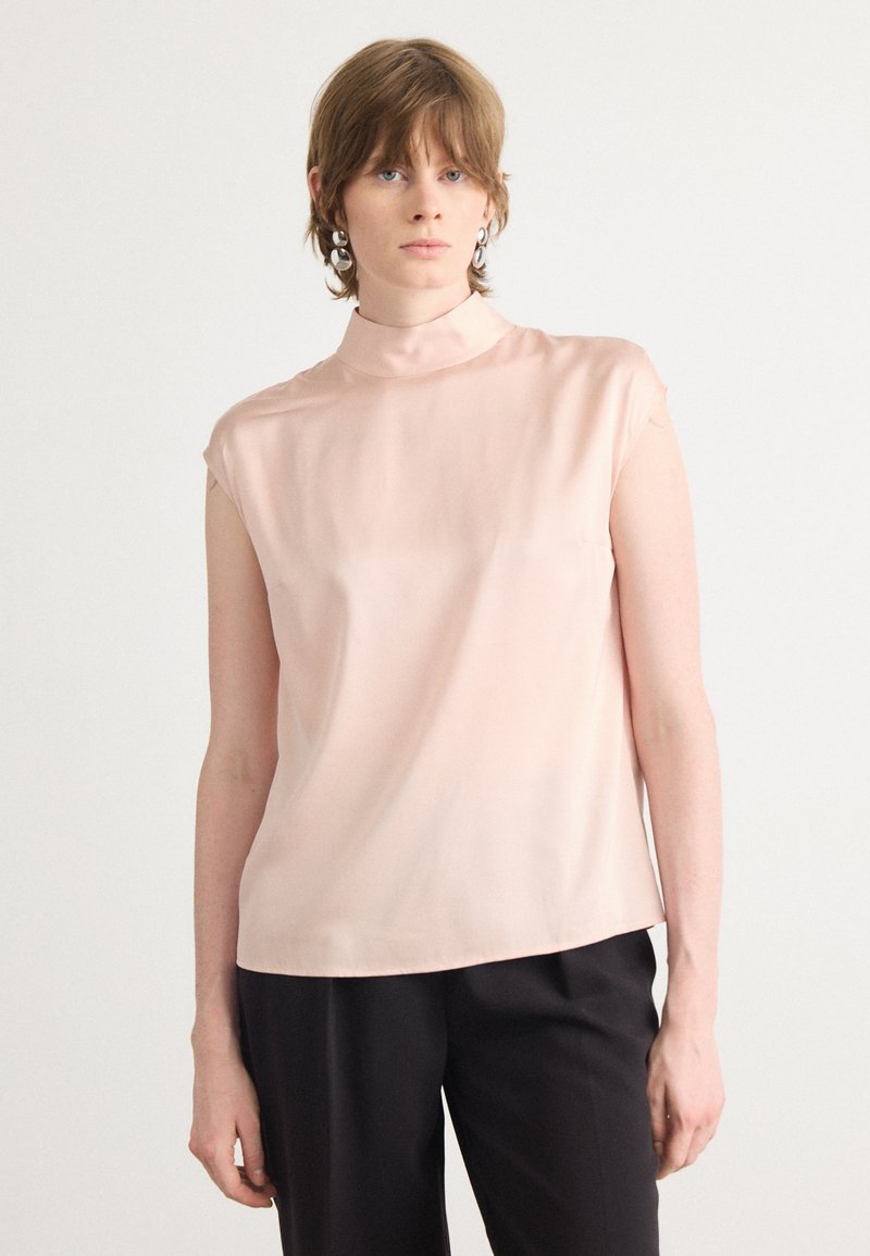 Top senza maniche, con collo alto, realizzato in morbido satin di un delicato rosa chiaro. Presenta un fit rilassato con una texture liscia e dettagli di cucitura minimi.