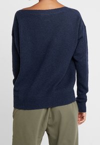 Pull surdimensionné bleu marine avec un large décolleté, tricot texturé, poignets et ourlet côtelés, vu de dos. Coupe décontractée avec épaules tombantes.