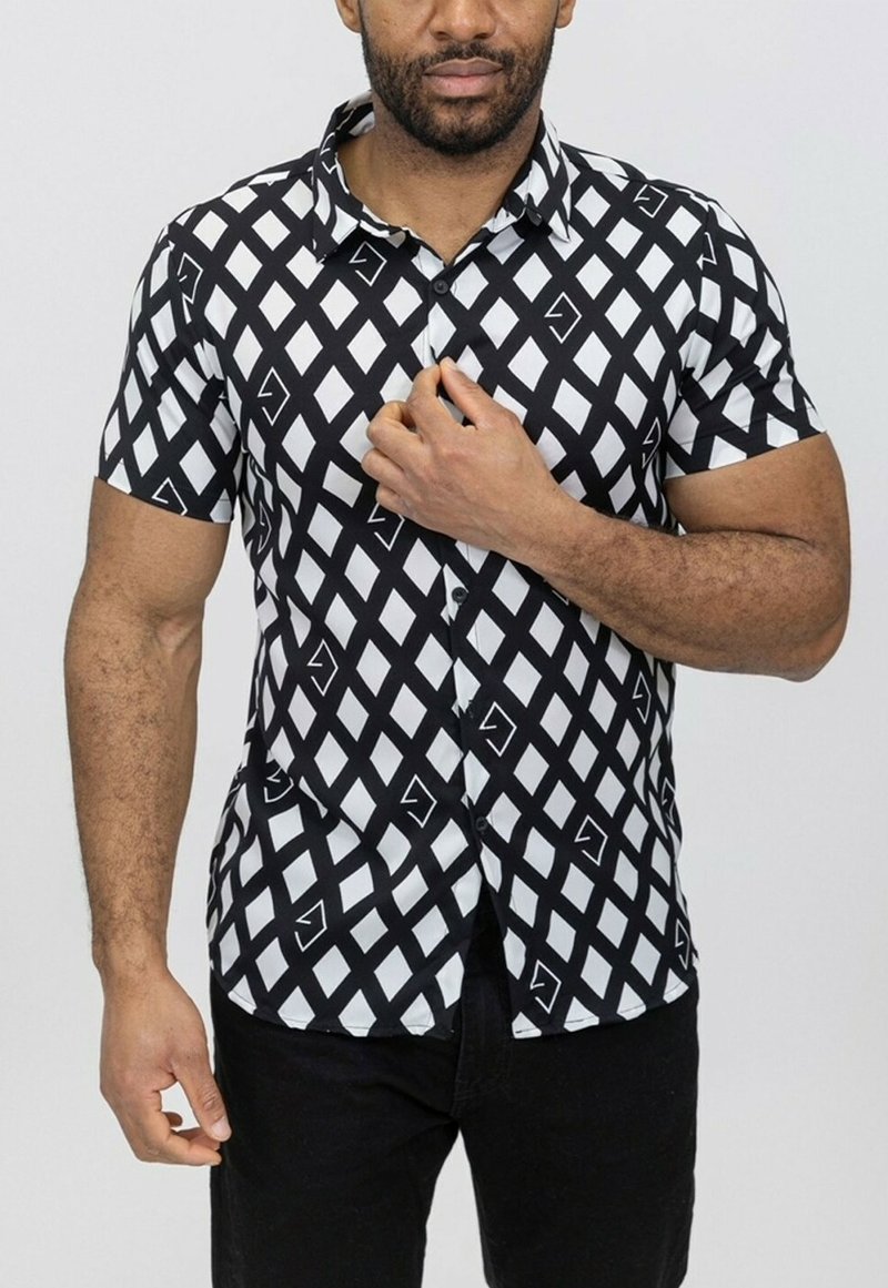 Chemise à manches courtes avec un motif en diamants noir et blanc, agrémentée d'accents géométriques. Fabriquée en tissu lisse et léger.