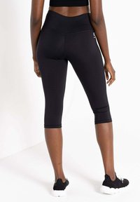 Schwarze Capri-Leggings aus dehnbarem Material, mit hohem Taillendesign, glatter Textur und verstärkten Nähten an den Säumen.