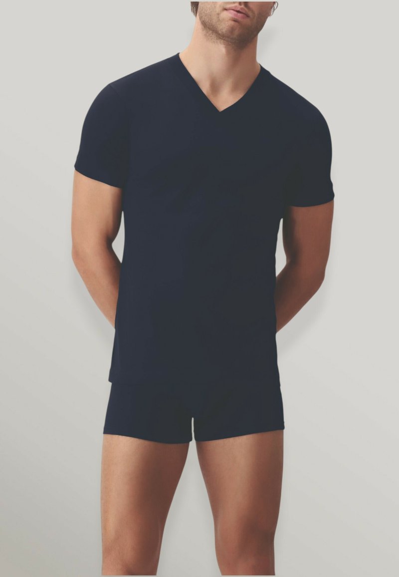 Maglietta a V in navy con maniche corte, abbinata a pantaloni corti aderenti coordinati. Realizzata in un tessuto morbido, offre un design elegante e minimalista.