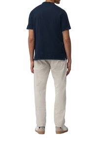 Marineblauw katoenen T-shirt met korte mouwen en een ronde hals, gecombineerd met crèmekleurige broeken en beige sneakers.