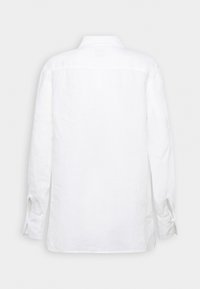 Biała lniana koszula z długim rękawem, z zadziornym kołnierzem, zapięciem na guziki i prostym krojem. Minimalistyczny design z teksturowanym wykończeniem.